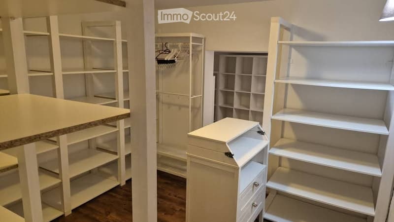 Empty room with white built-in shelving units and a small table with a granite countertop. No furniture or personal items present.
