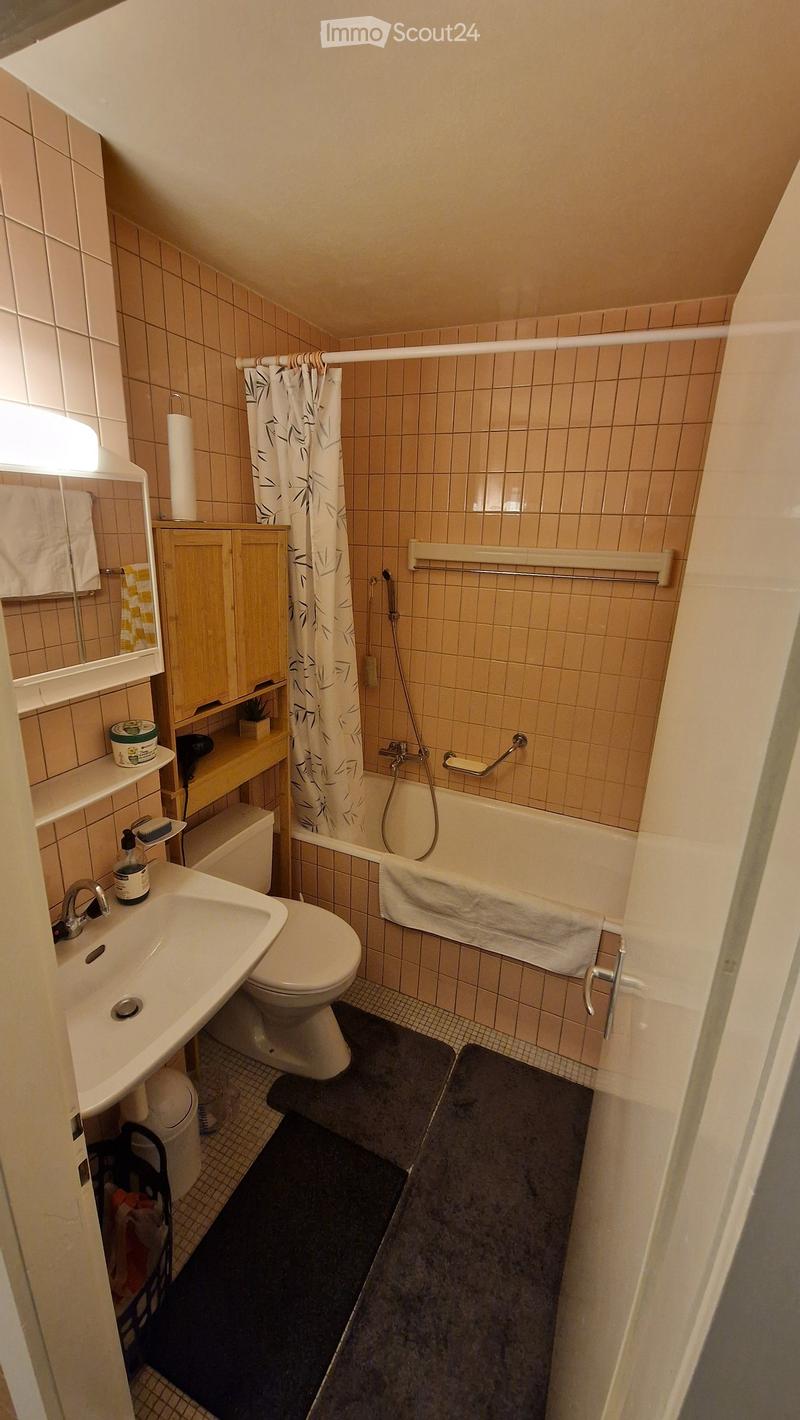 Bathroom with bathtub, toilet, sink, shelves, and a shower curtain.