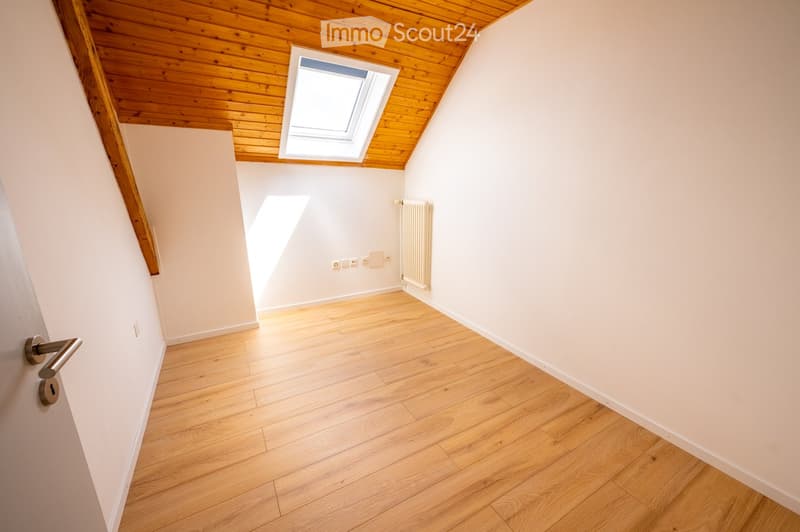 Empty room with wooden flooring, white walls, and a skylight window. No furniture or equipment present.