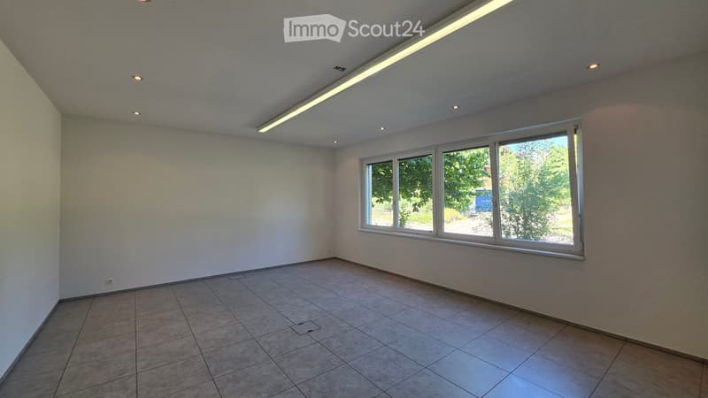 Empty room with tiled floor, white walls, and large windows letting in natural light. No furniture or equipment present.