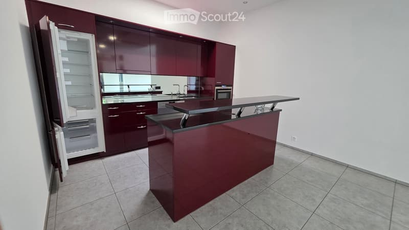 Modern kitchen with dark red cabinets, a central island, a refrigerator, sink, and oven.