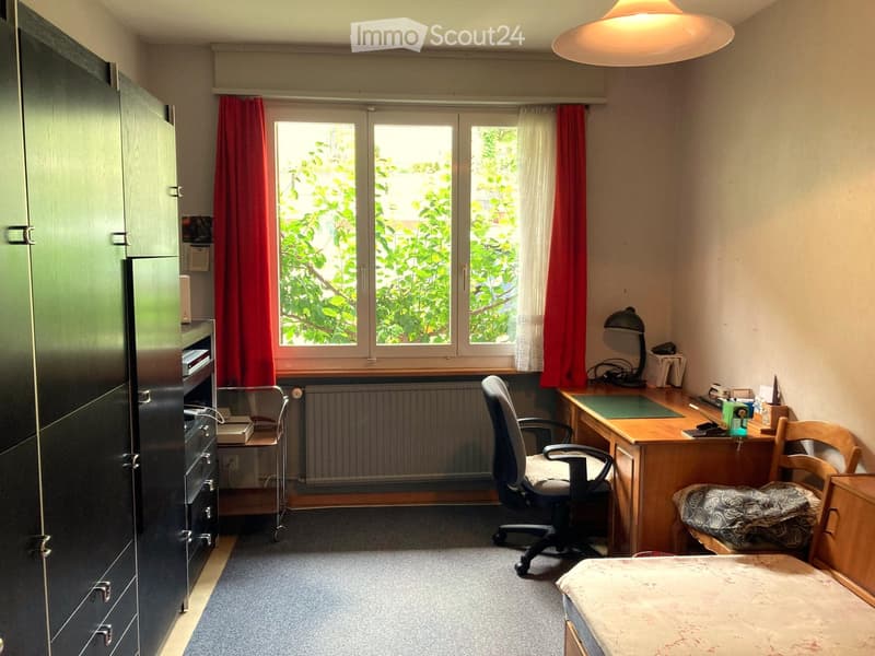 A room with a desk, chair, lamp, bed, wardrobe, drawers, radiator, basket, bag, book, and outlet.