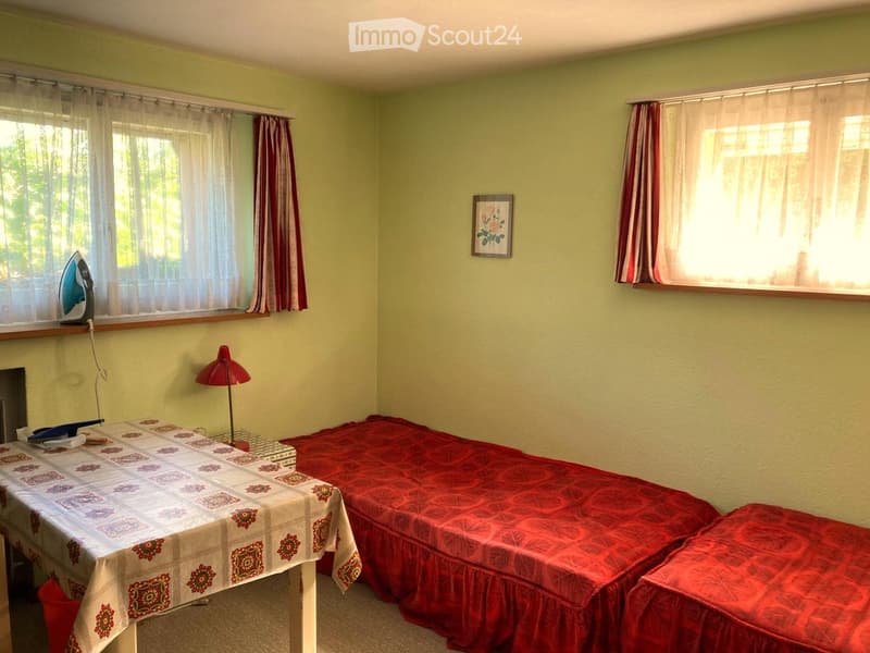 Small room with two single beds, a table, a lamp, and an iron on the window sill.