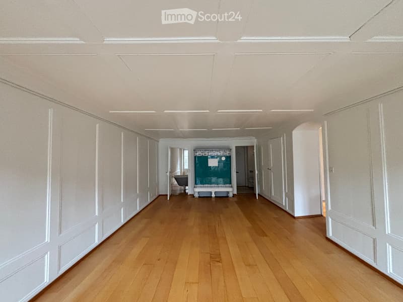 Empty hallway with wooden flooring, white walls, and multiple doors leading to other rooms.