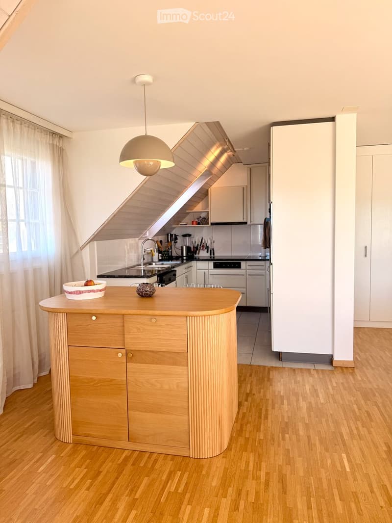 Modern kitchen with wooden island, white cabinets, stainless steel appliances, and pendant lighting.
