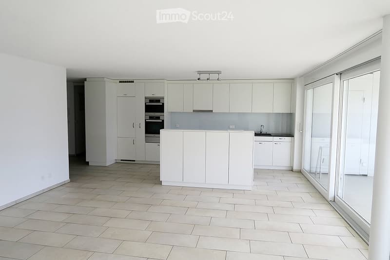Modern, minimalist kitchen with white cabinets, a central island, and built-in appliances including an oven and sink.
