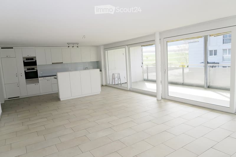 Modern, minimalist kitchen with white cabinets, stainless steel oven, and large sliding glass doors leading to a balcony.