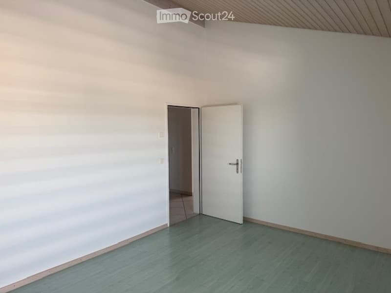 Empty room with light blue flooring, white walls, and a single white door leading to another space.