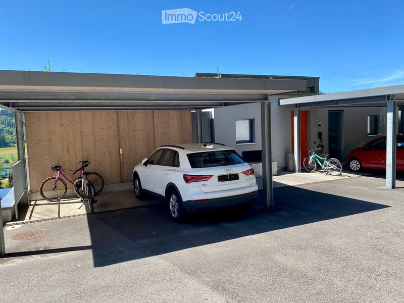 Modern garage with a covered parking area, featuring a white SUV, bicycles, and a red car parked inside.