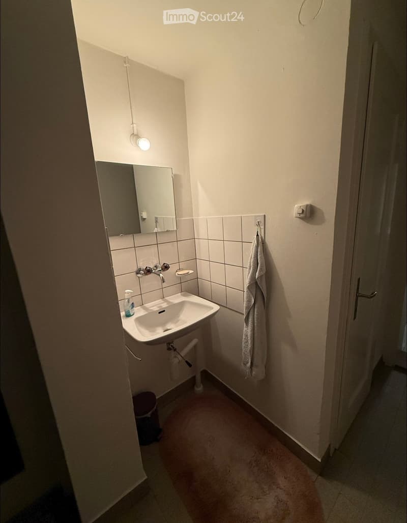Small bathroom with a white sink, mirror, towel, and light fixture above the sink.