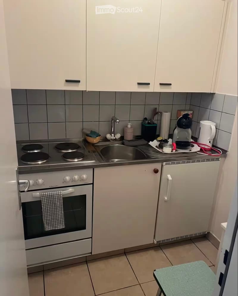 Compact kitchen with white cabinets, stainless steel appliances, and a small sink area.