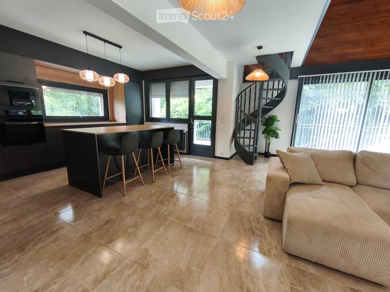 Modern open-plan living and dining area with a sofa, coffee table, kitchen island, and pendant lights.