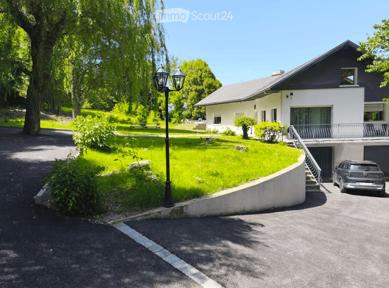 Modern two-story house with white and dark gray exterior, garage, and a well-maintained lawn.