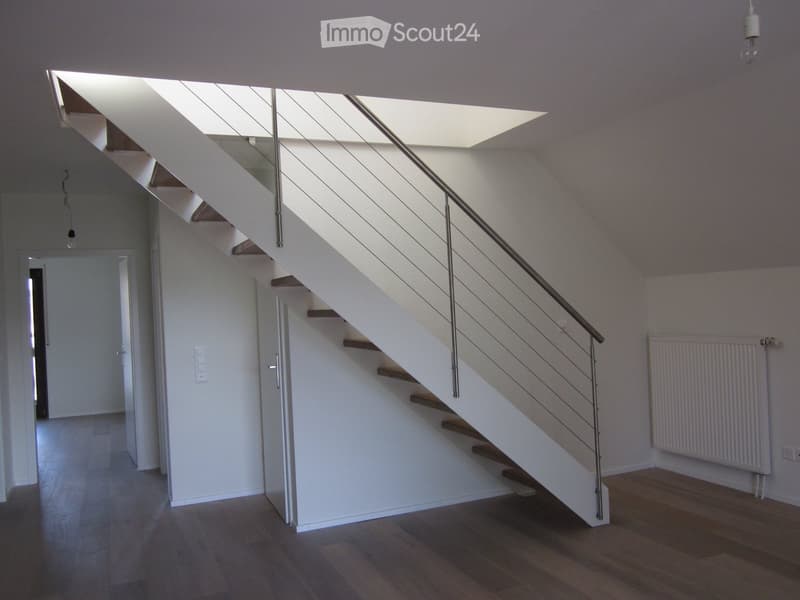Staircase with wooden steps and metal railing, white walls, white ceiling, light fixture