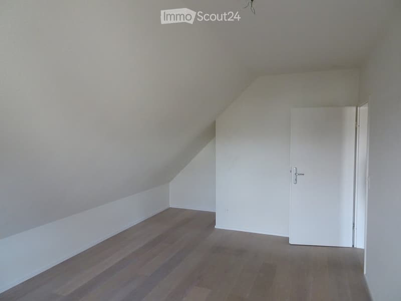 white walls, wooden floor, slanted ceiling, door, empty room