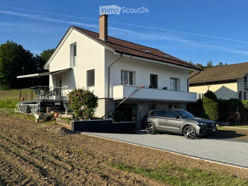 Two-story house with white exterior, brown roof, garage, and parking area.