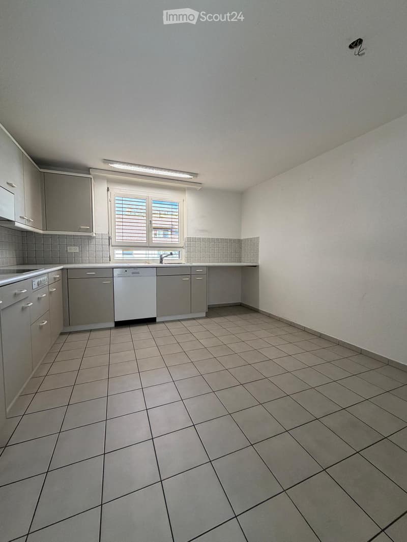 Empty kitchen with tiled floor, white cabinets, sink, dishwasher, and window with blinds