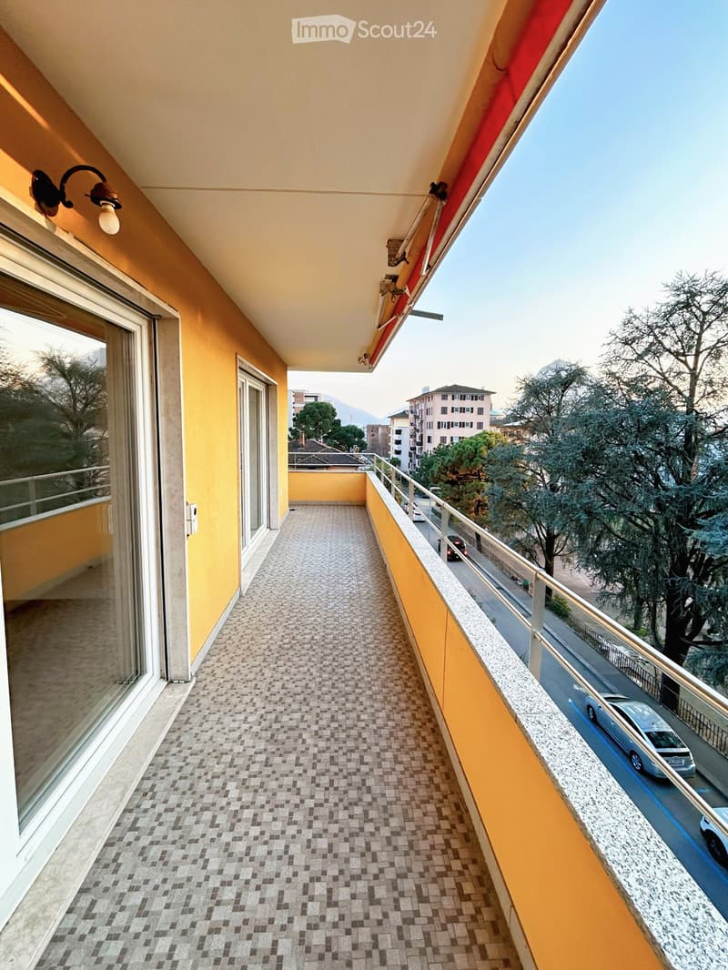 Balcony with yellow walls, tiled floor, metal railing, and scenic city view.