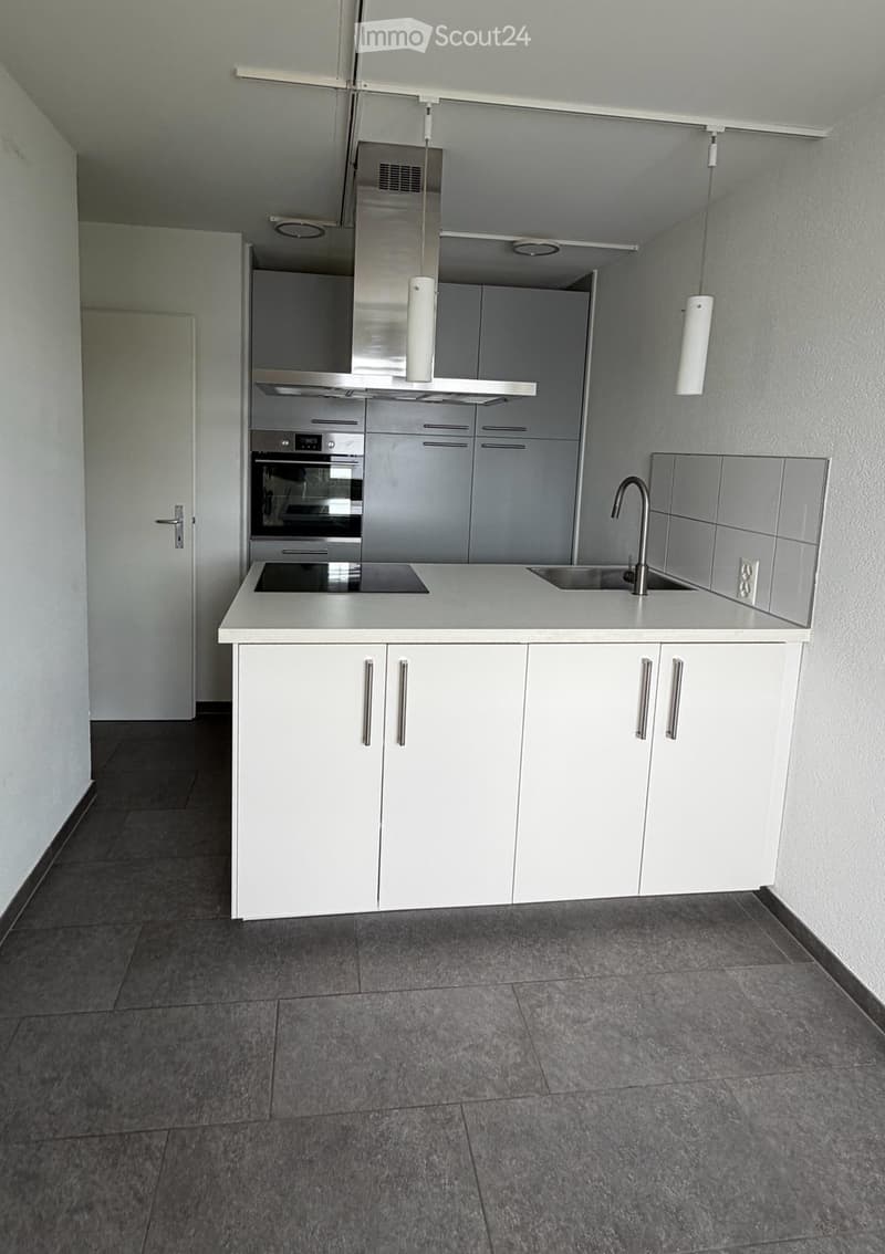 Modern kitchen with white cabinets, stainless steel appliances, and a central island with a sink and faucet.