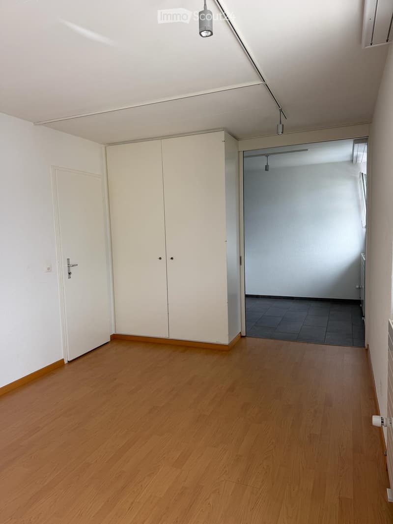 Empty hallway with wooden flooring, white walls, and a closed door leading to another room.
