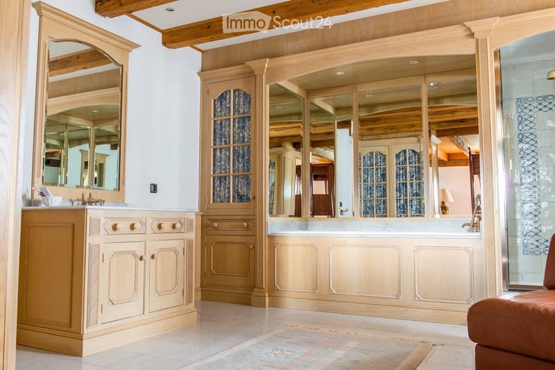 Elegant bathroom with wooden cabinetry, a large mirror, a sink, and a bathtub, featuring exposed wooden beams on the ceiling.