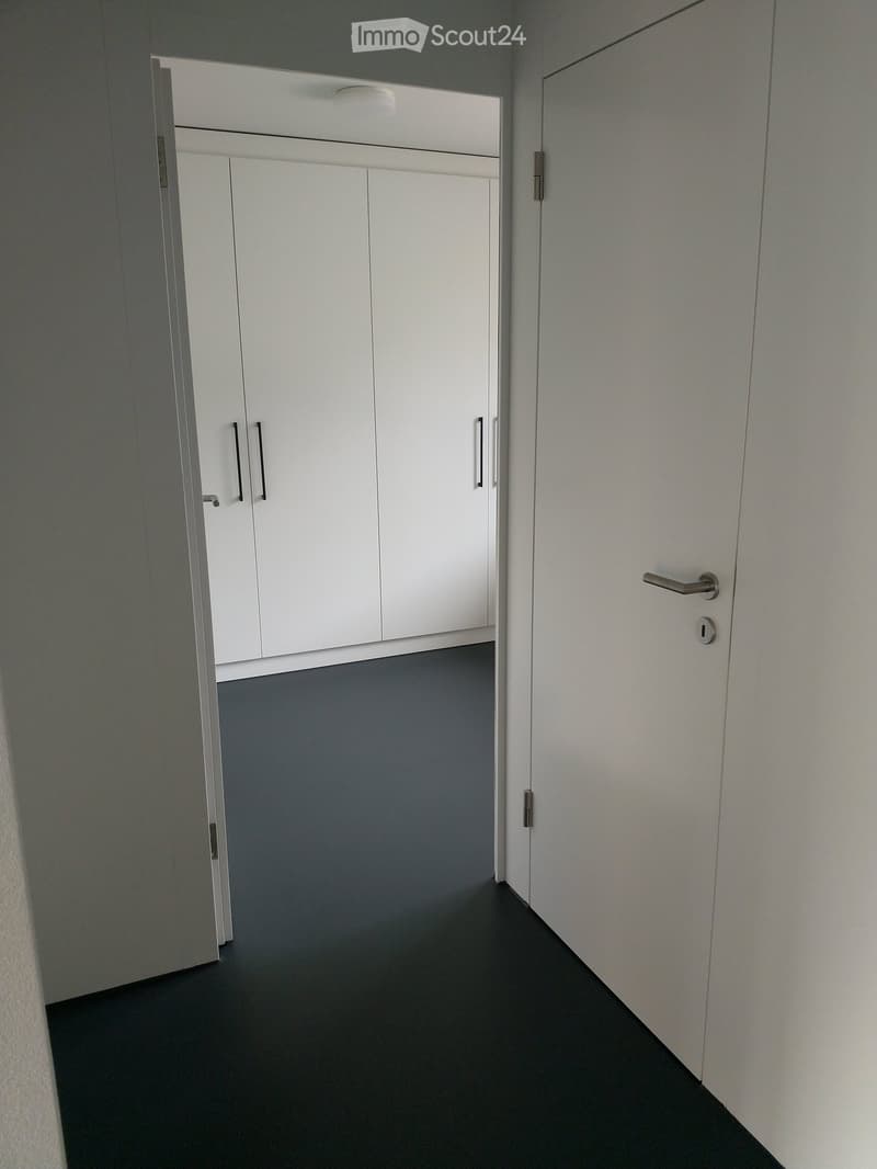 The image shows a hallway with two sets of white sliding doors, dark floor, white ceiling.