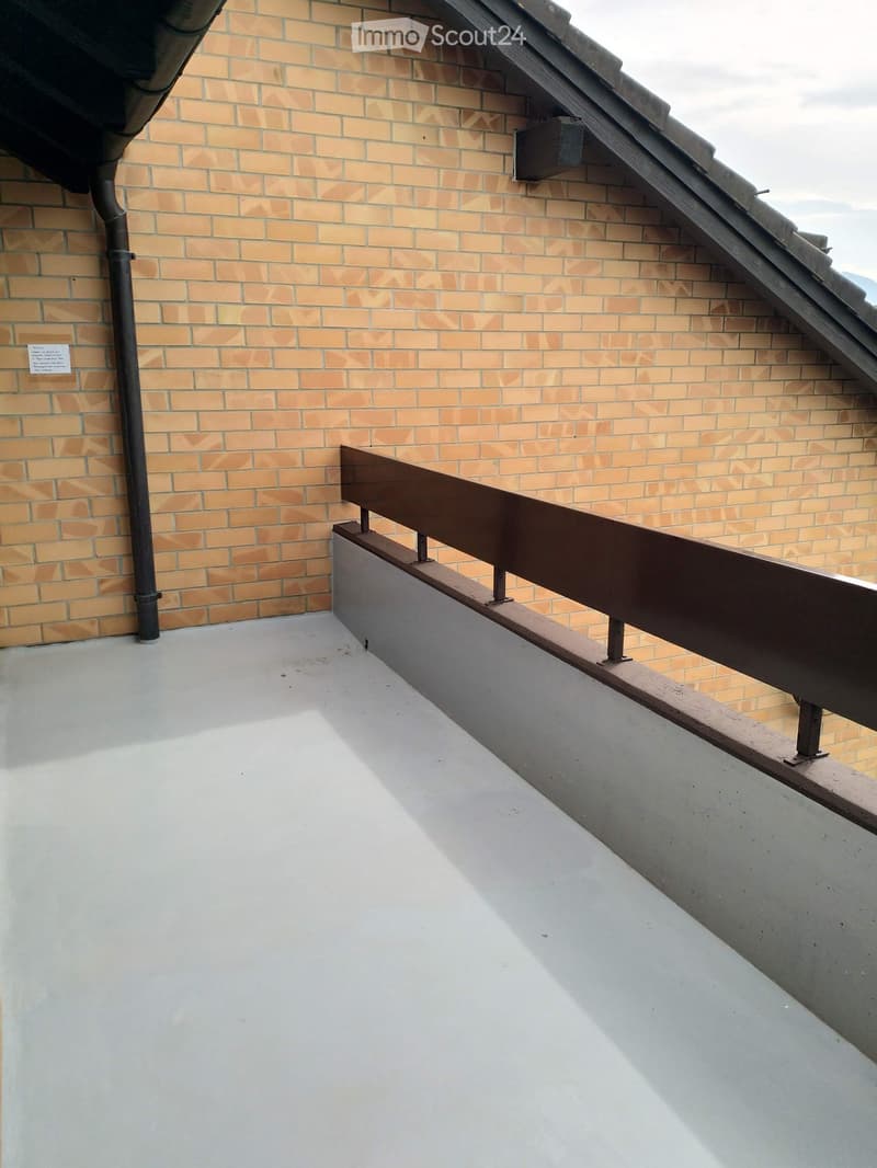 wooden railing on terrace with brick wall, drain pipe on the left