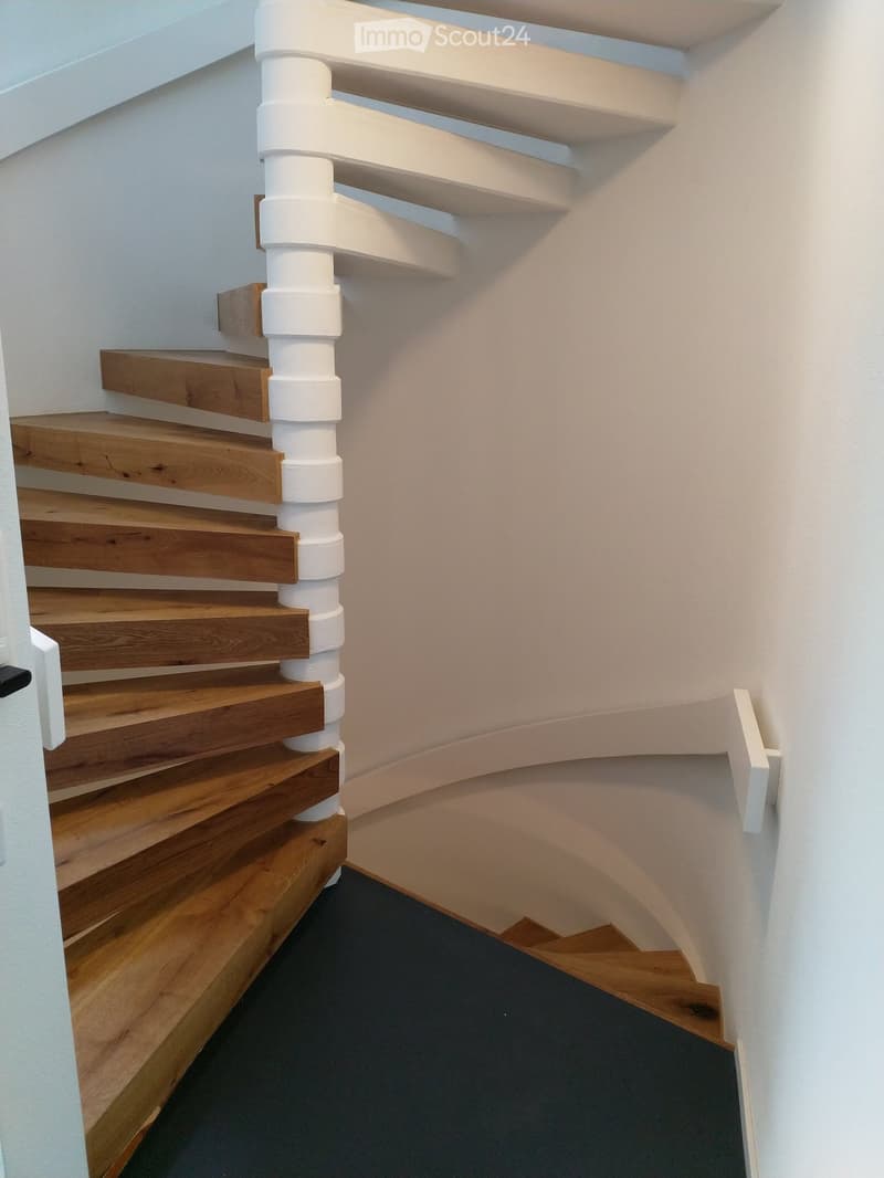 Wooden staircase with a white banister, brown wooden stairs, and a gray carpet.