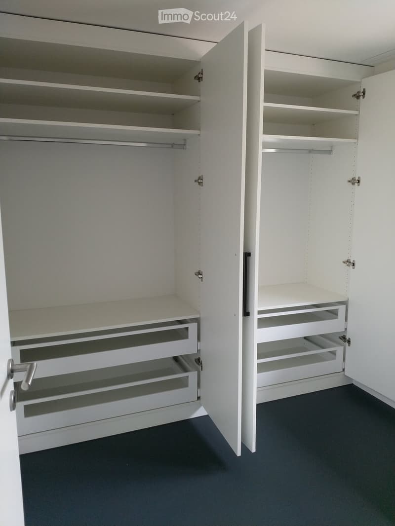 empty walk-in closet with hanging rods, drawers and shelves