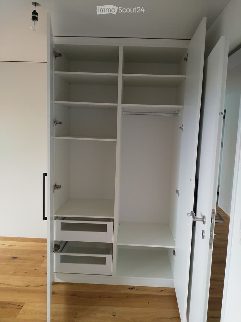 empty white wardrobe with double doors, two drawers at the bottom, hanging bar, multiple shelves