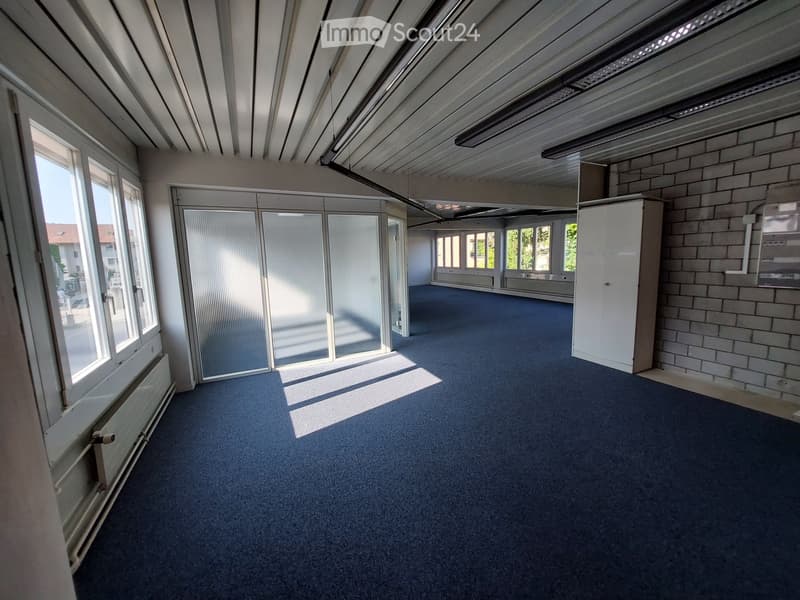 Empty room with grey carpet, large windows, white walls, and a white cabinet. No furniture or equipment present.