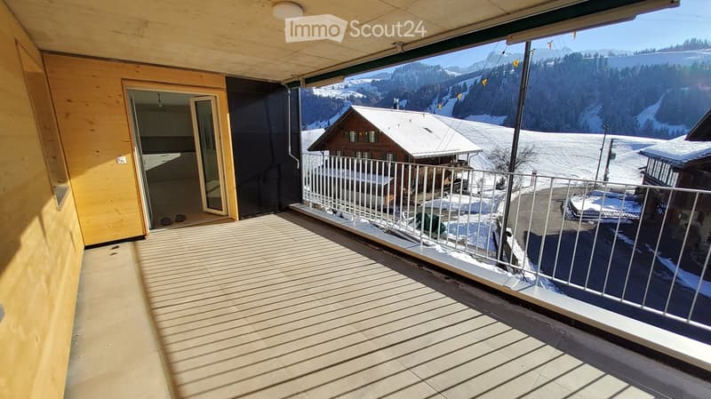 Balcony with wooden decking, metal railing, and scenic mountain view.