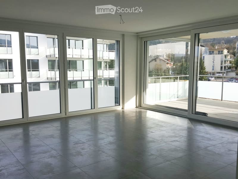 Empty room with large sliding glass doors leading to a balcony, tiled floor, and modern white walls.