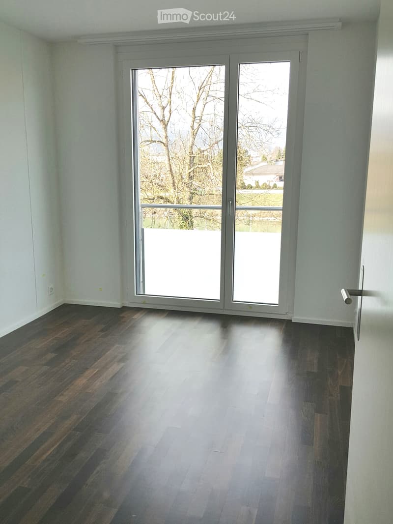 Empty room with wooden flooring and large sliding glass doors leading to an outdoor area.