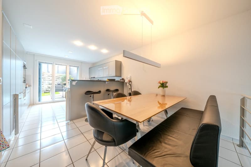 modern dining room with white tile flooring, gray countertops, and a large wooden table with chairs