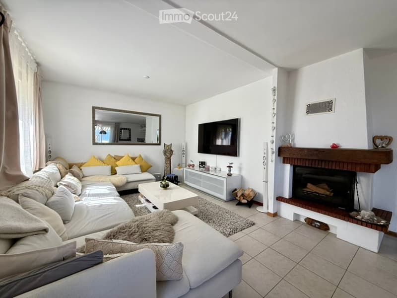 Modern living room with a large sectional sofa, coffee table, fireplace, TV, and decorative items.