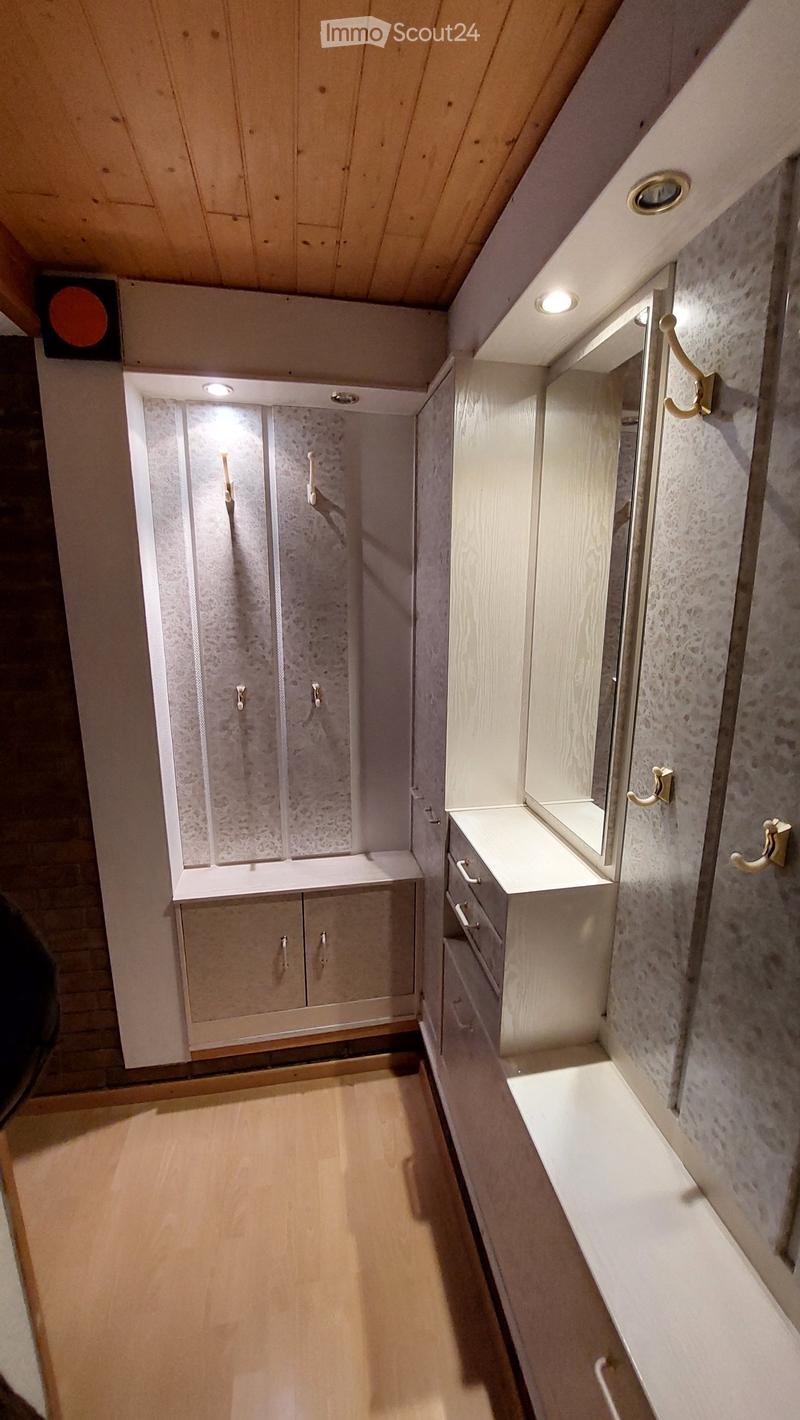 Narrow hallway with wooden flooring, white walls, built-in cabinets, and a small sink area with a mirror and drawers.