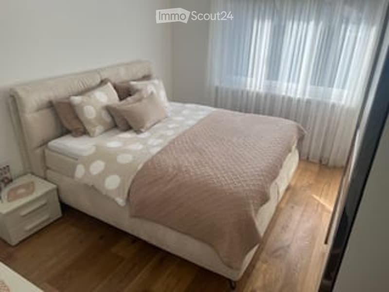 A bedroom with a bed, pillows, and a nightstand with a lamp