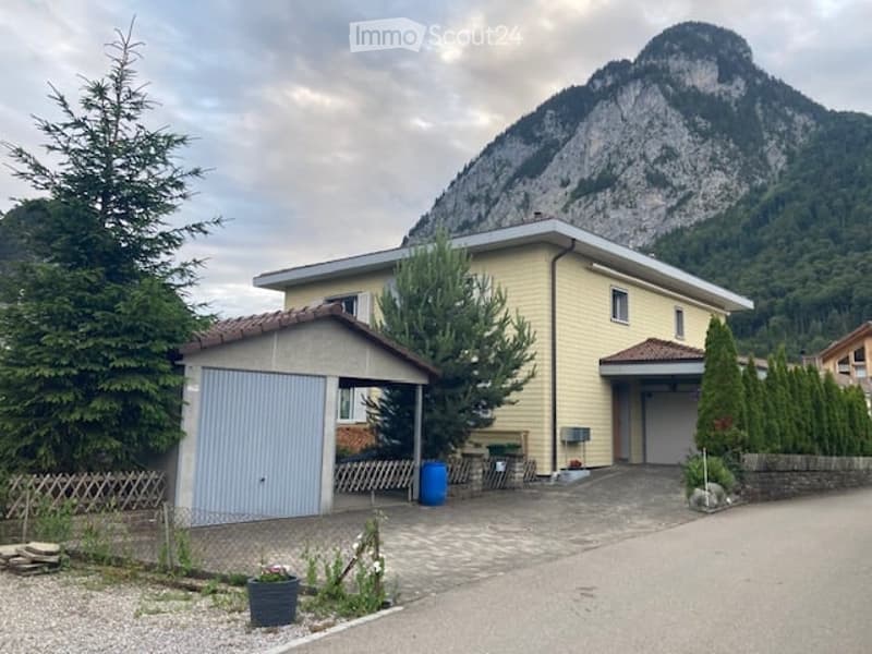 Two-story house with yellow siding, garage, and scenic mountain view in the background.