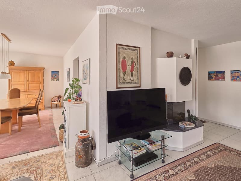 white walls, fireplace, flat screen TV, glass table, carpet, wooden cabinet, dining table, chairs, paintings, potted plants
