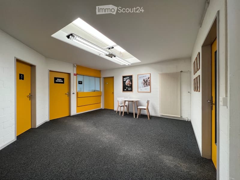 room with white walls, grey carpet, bright ceiling, 2 doors, white radiator, tables and chairs