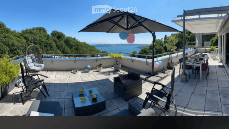 Outdoor terrace with table, chairs, umbrella, plants, and a view of the sea
