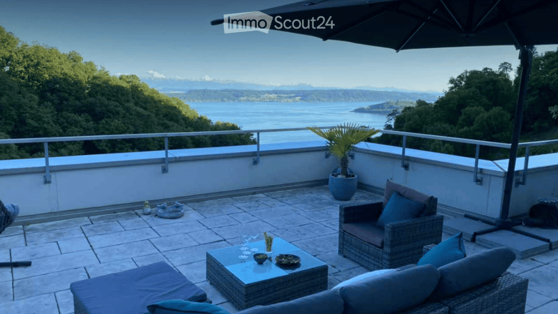 Outdoor seating area with a table, chairs, and a couch, a potted plant, a view of the sea and mountains