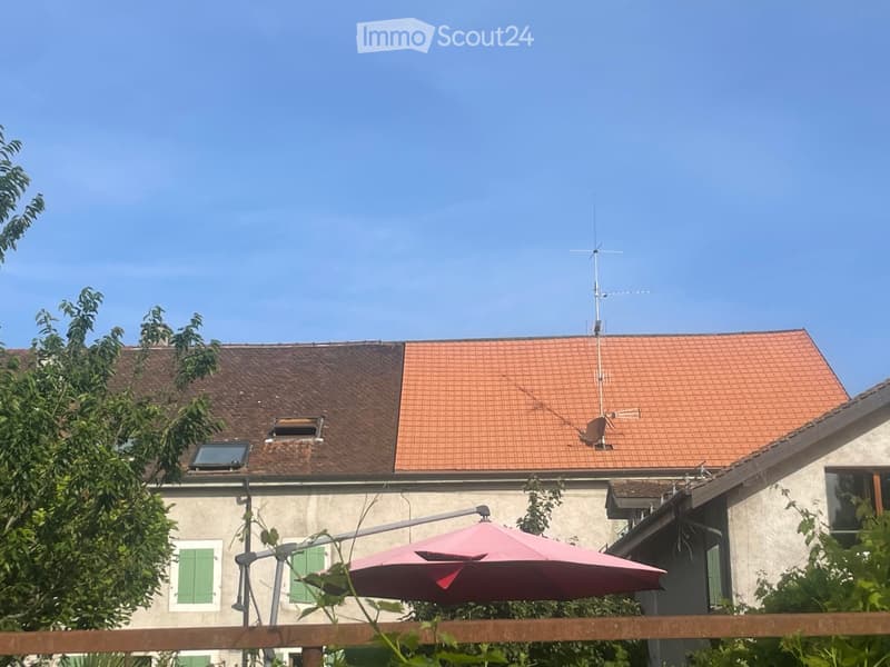 Two-story house with red-tiled roof, visible antenna, and solar panel on the roof.