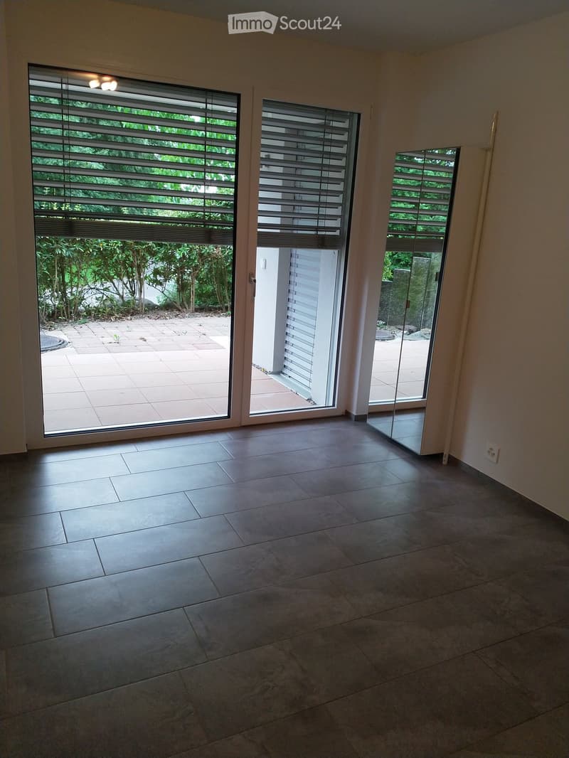 Empty room with tiled floor, large windows with blinds, and sliding glass doors leading to an outdoor patio.