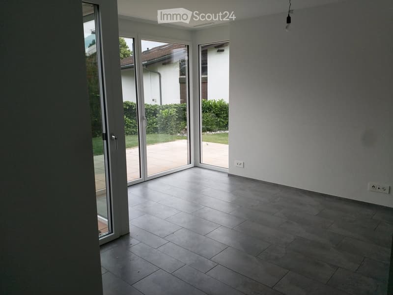 Empty room with tiled floor, large sliding glass doors leading to a patio, and white walls.