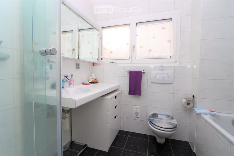 white tiled walls, glass door shower, white sink, storage cabinet, toilet, bathtub