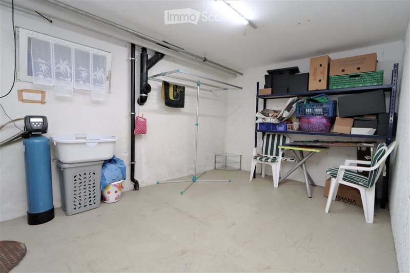A storage room with a washing machine, shelves, a desk, chairs, and a clothes rack