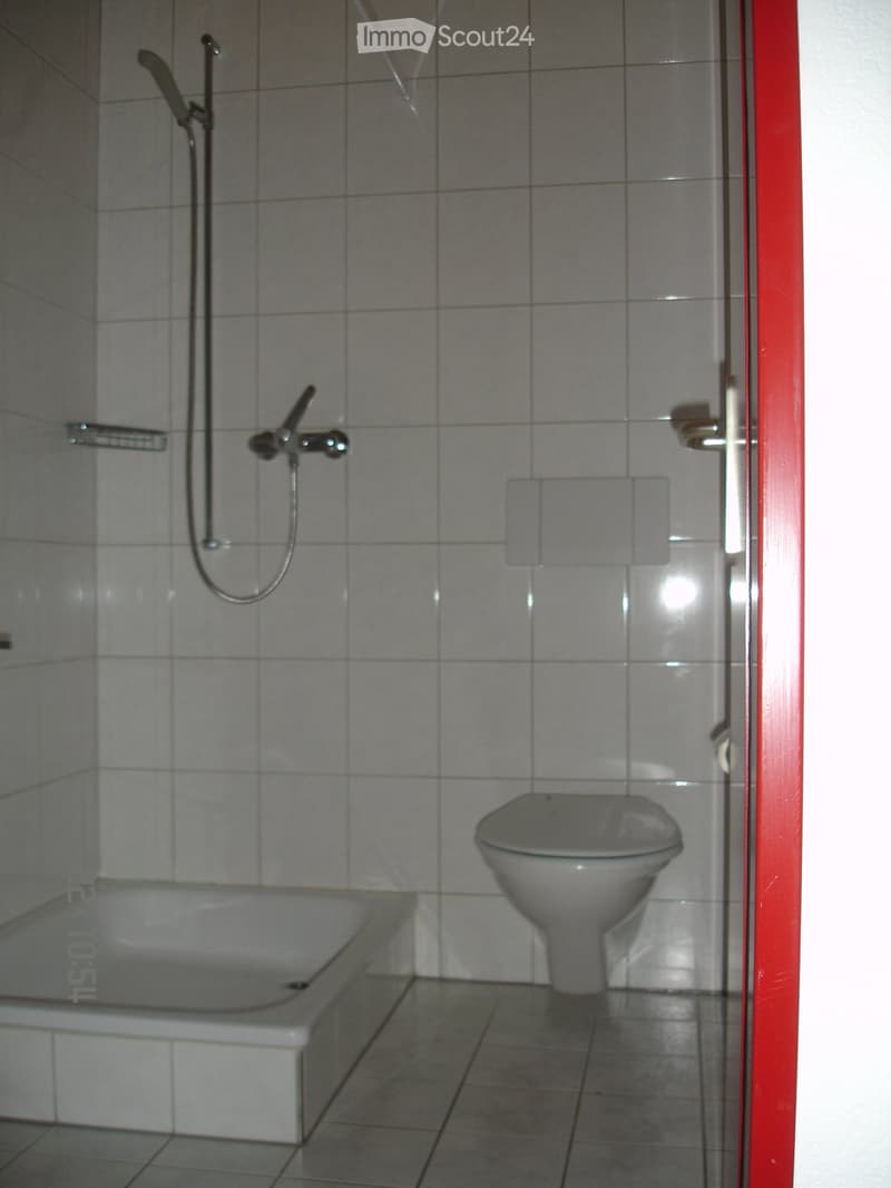 Bathroom with tiled walls and floor, featuring a bathtub, toilet, and a shower with a handheld sprayer.
