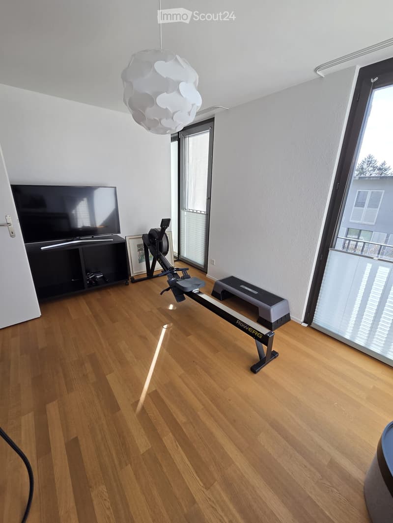 Furnished Room. Modern room with wooden flooring, large windows, television, exercise bike, and rowing machine.